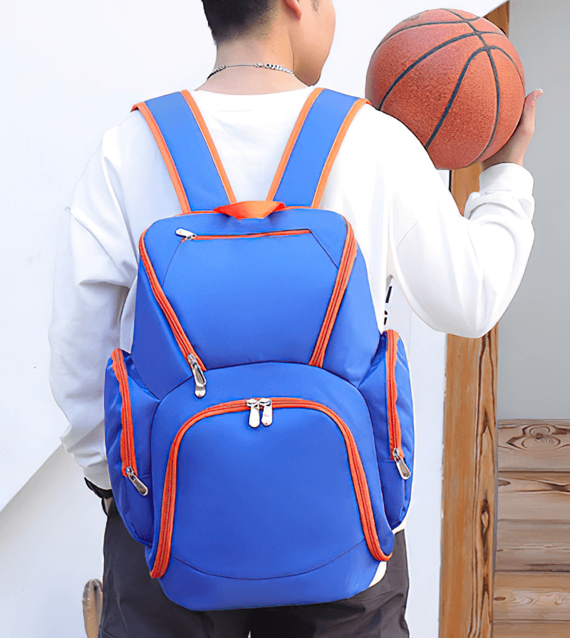 Person carrying blue and orange waterproof lightweight large capacity football backpack SF0870 with ball.